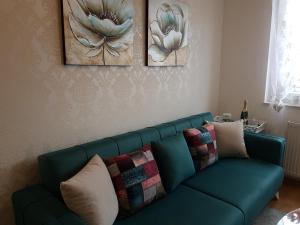 eine grüne Couch in einem Wohnzimmer mit zwei Bildern an der Wand in der Unterkunft Kraljev Park (King's Park) in Novi Sad