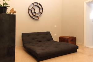 un sofá en una sala de estar con un reloj en la pared en 4 Balconi rooms-Boutique B&B, en Lecce