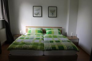 a bed with green and white blankets and pillows at Kleines, gemütliches Häuschen in Mönchengladbach