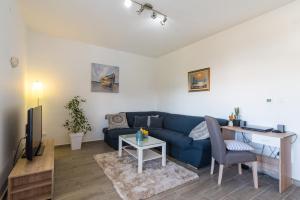 ein Wohnzimmer mit einem blauen Sofa und einem Tisch in der Unterkunft Apartment Okrug Gornji - Trogir with Sea View in Trogir