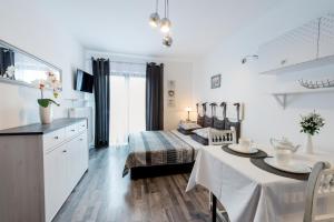 biała sypialnia z łóżkiem i stołem z tableablish w obiekcie Apartamenty Królewska Kwatera w mieście Zamość