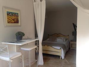 a bedroom with a bed and a desk and a table at La Petite perle, balnéo en supplément, le Clos des Perles in Tourtour