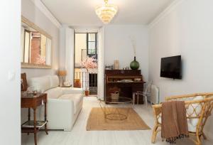 a living room with a white couch and a tv at Elegante y espacioso, junto a la Plaza Mayor in Madrid