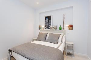 a white bedroom with a bed with two pillows at Elegante y espacioso, junto a la Plaza Mayor in Madrid