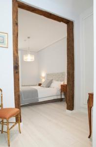 a white bedroom with a bed and a chair at Elegante y espacioso, junto a la Plaza Mayor in Madrid