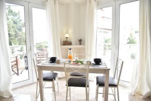 a dining room with a table and chairs and windows at KyMa Studios and Suites in Asprovalta