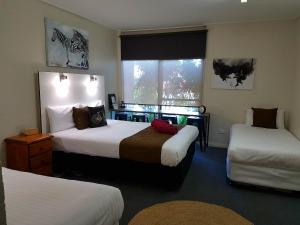 Habitación de hotel con 2 camas y ventana en Bidgee Motor Inn en Hay