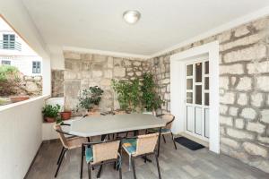un patio con mesa, sillas y pared de piedra. en Apartmani Sršen, en Blace