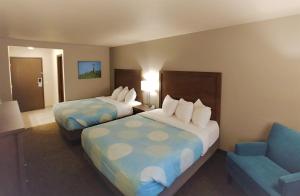 a hotel room with two beds and a chair at Baymont by Wyndham Monte Vista in Monte Vista