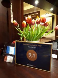 una placa con un jarrón de flores sobre una mesa en Hotel Batory, en Tłuszcz