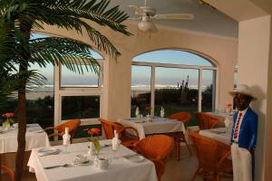 a man is standing in a restaurant with tables at The Beach Villa in Melkbosstrand