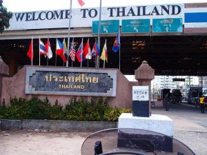 ein Willkommen auf dem Thai-Schild vor einem Gebäude mit Flaggen in der Unterkunft Ct HOMESTAY in Changlun
