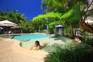 a woman laying in a swimming pool in a resort at Portobello By The Sea in Caloundra