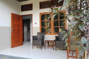 a porch with chairs and a table and a door at Sandat Hotel Legian in Legian