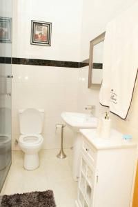 La salle de bains blanche est pourvue de toilettes et d'un lavabo. dans l'établissement Westland Villa, à Accra