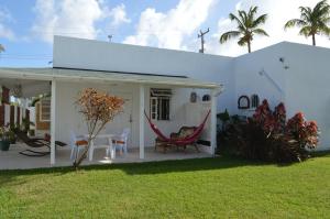 Casa blanca con porche con sillas y mesa en Tropical Gecko Studio - Sweet Jewel Apartments, en Christ Church