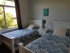 1 dormitorio con 2 camas y ventana en The Lake Escape, en Mannering Park