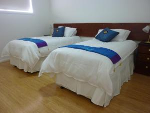 two beds in a bedroom with blue pillows on them at Lincoln View Holiday House in North Shields