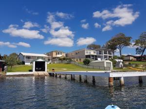 a dock on a body of water with houses at The Lake Escape in Mannering Park