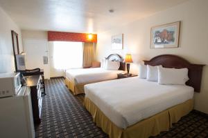 a hotel room with two beds and a television at Queens Inn Anaheim in Anaheim