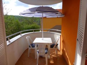 uma mesa e cadeiras numa varanda com um guarda-sol em Apartments Kvesić em Šilo