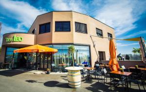 un ristorante con tavoli e ombrelloni di fronte a un edificio di Cafe-Restaurant LEO a Kalsdorf bei Graz