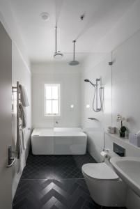 a bathroom with a toilet, bathtub, sink and tub at Mrs Banks Hotel in Sydney