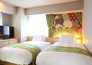 two beds in a hotel room with a tv at Hotel Wing International Premium Kanazawa Ekimae in Kanazawa