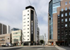 a tall white building on a city street with buildings at Hotel Emit Ueno in Tokyo