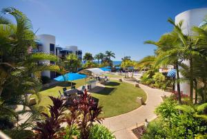 un parque con mesas, sombrillas y palmeras en Headland Tropicana Resort, en Alexandra Headland