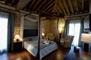 a bedroom with a canopy bed and a chair at El Pontifical in Los Santos de la Humosa