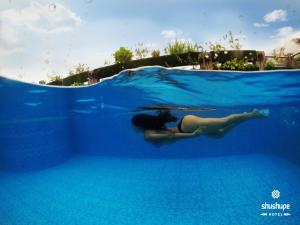 une femme qui se couche à l'eau dans une piscine dans l'établissement Shushupe Hotel, à Tingo María