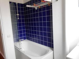a blue tiled bathroom with a white bath tub at Gite Clemenceau in Rouen