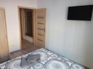 a bedroom with a bed and a flat screen tv at Nordic Apartamenty Grochowa in Białystok