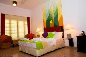 a bedroom with a bed with a colorful painting on the wall at The Kent in Tissamaharama