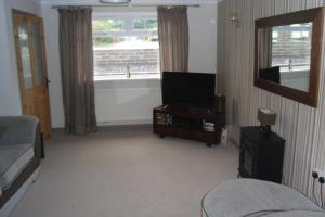 een woonkamer met een flatscreen-tv en een bank bij Princetown Cottage in Nant-y-bwch