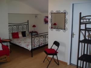 1 dormitorio con cama, silla y espejo en B&B Le Bois Berranger, en Saint-Urbain