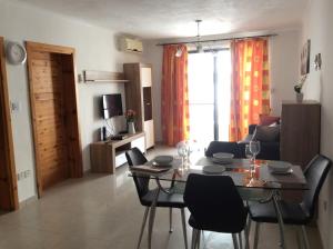 a living room with a table and chairs in a room at Comfort Apartment No. 16, Daffodil Court in St Paul's Bay