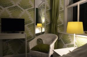 a living room with a chair and a television at Audley Guest House in Llandudno