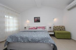 sypialnia z łóżkiem i zielonym krzesłem w obiekcie Apartments Sorriso w Rovinj
