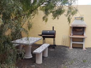 een grill en twee banken naast een gebouw bij Casa Ary in Tesejerague