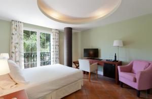 a bedroom with a bed and a desk and a chair at Hotel MR Les Rotes in Denia +131 photos