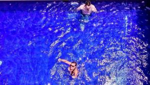 two people swimming in a pool of blue water at Castaway Hostel in Canggu