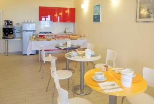 uma sala de jantar com duas mesas e cadeiras e uma cozinha em La Perla Del Conero Affittacamere em Numana