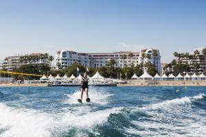 a person water skiing in the water near a beach at Hôtel Barrière Le Majestic Cannes in Cannes