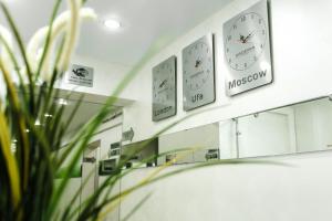 Baño con relojes en la pared sobre un espejo en Гостиница Arderia, en Ufa