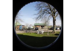 ein rundes Fenster mit Blick auf einen Park mit einem Baum in der Unterkunft Ferienhof Augustenhöhe in Fehmarn