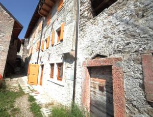 Albergo Diffuso Valcellina e Val Vajont in Erto في Erto: مبنى حجري قديم عليه باب اصفر