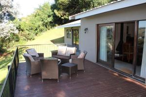 a patio with chairs and a table on a deck at Birdsong Cottages in Champagne Valley