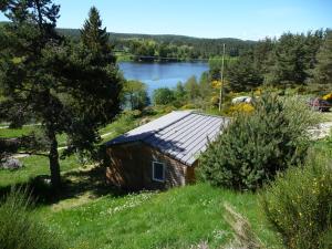 een kleine houten hut in een veld met een meer bij Le Chalets du lac de Ganivet in Ribennes